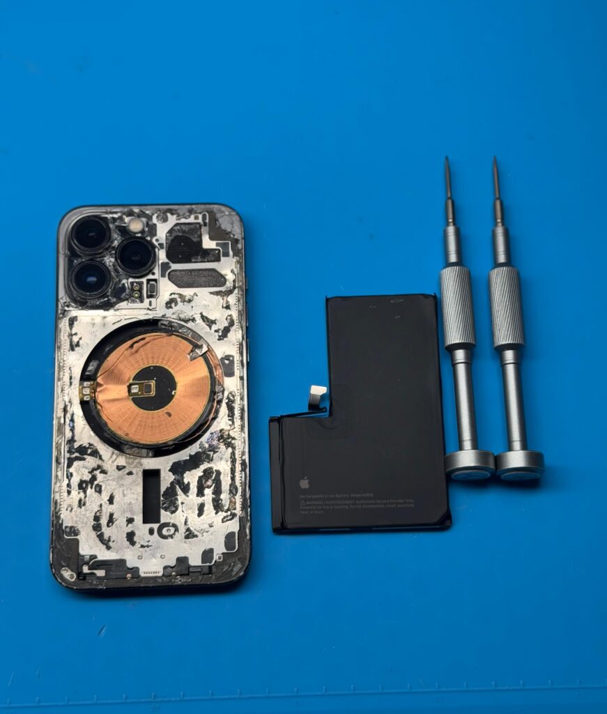 Componenti interni di uno smartphone durante una riparazione: scocca, batteria e cacciaviti di precisione